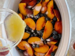 Blueberries and Peaches being covered with sugar and lemon juice for blueberry peach crisp