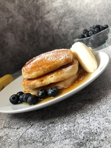 pancakes on a plate with blueberries and bananas