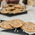white chocolate macadamia nut cookies sitting on a black plater with parchment underneath