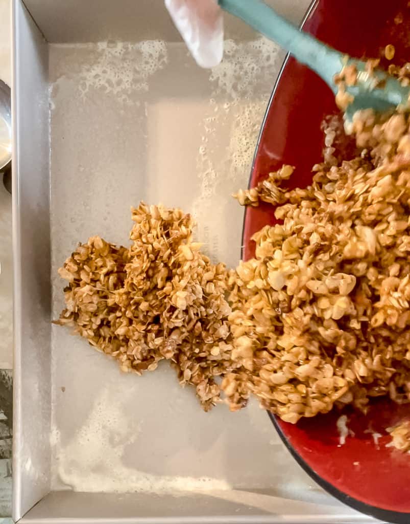 pouring granola bars into a pan