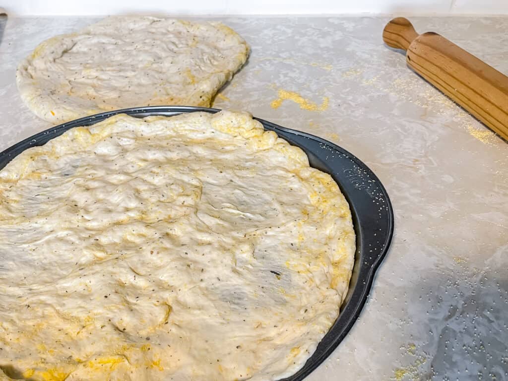 garlic and herb pizza dough on a pizza pan