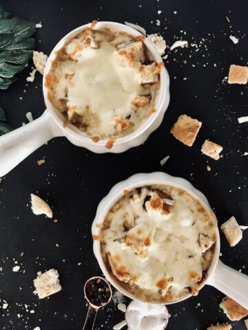 two bowls of French Onion Soup with cheese and bread surrounding it.
