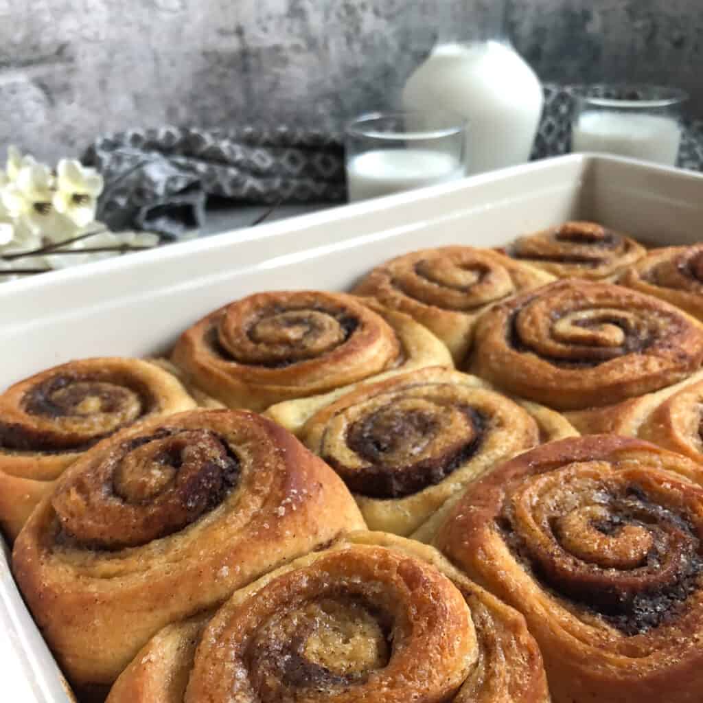 tray of cinnamon buns with milk in the background