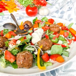 a platter of Greek salad with lamb meatballs.