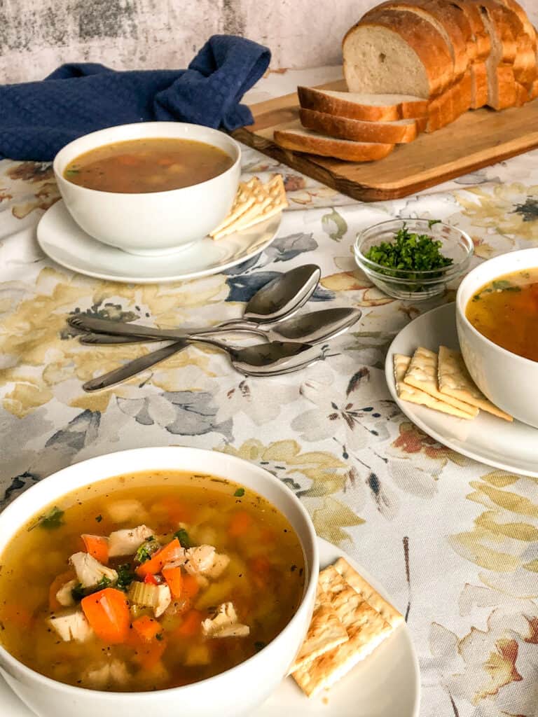 Table set with bowls of chicken noodle soup and fresh bread
