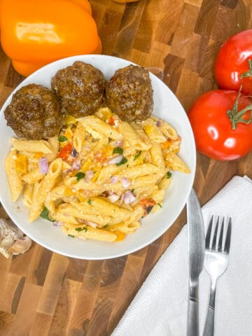 Greek meatball feta pasta in a bowl with ingredients surrounding it