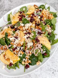 closeup photo of apple walnut spinach salad on a plate