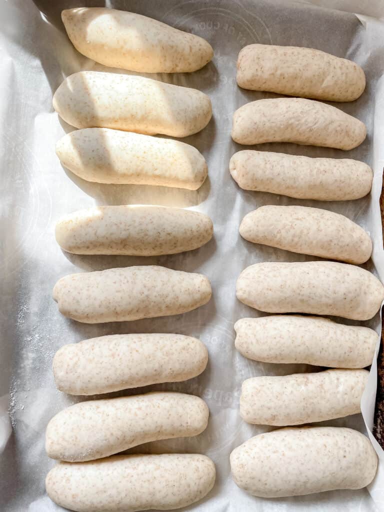 hot dog buns shaped on a sheet tray before baking