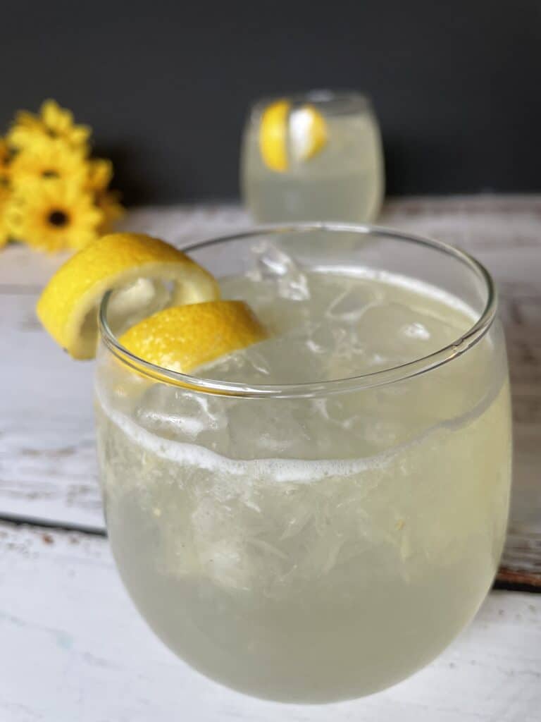 Close up of old fashioned lemonade with another glass behind it and sunflowers