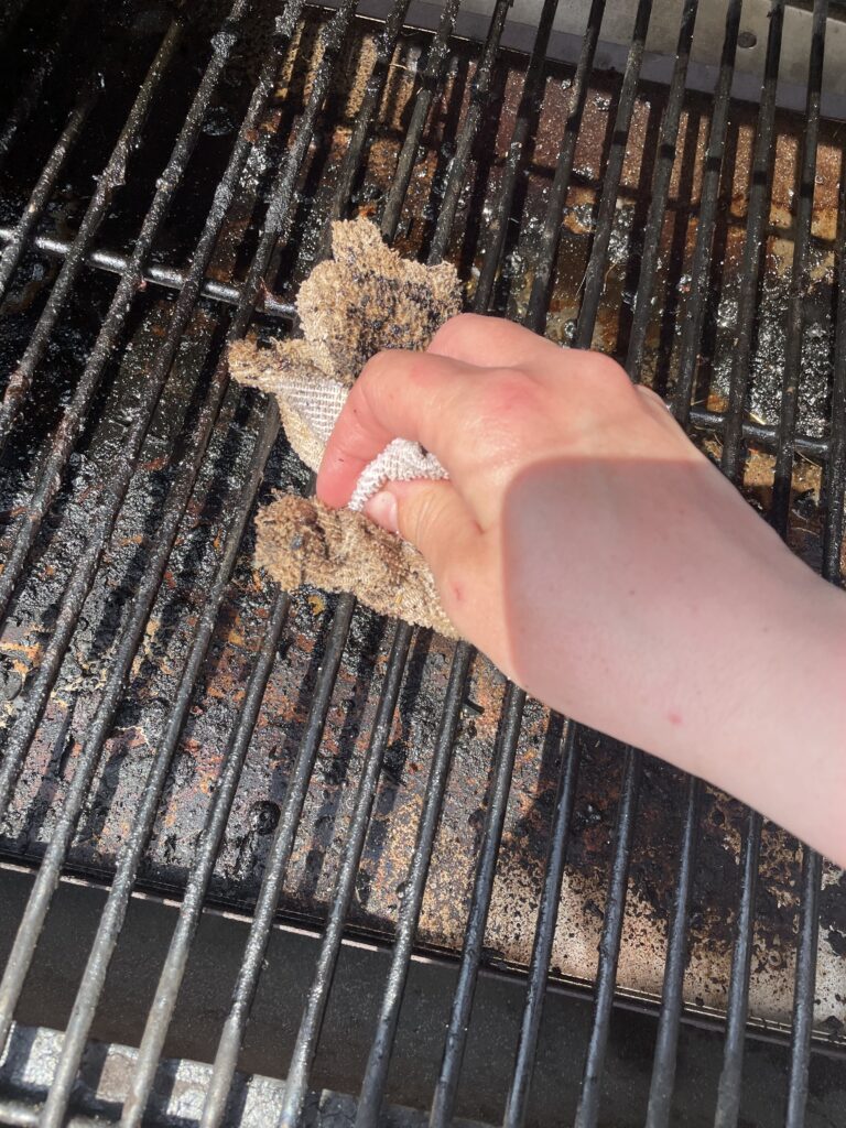 Scrubbing a dirty traeger grill grate with a microfiber cloth