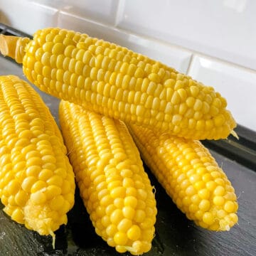 4 cobs of simple sweet corn on a black slate plate
