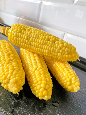 4 cobs of simple sweet corn on a black slate plate