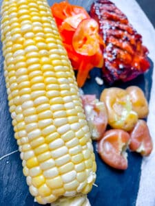 corn on the cob served with smashed potatoes, salad and a grilled pork chop