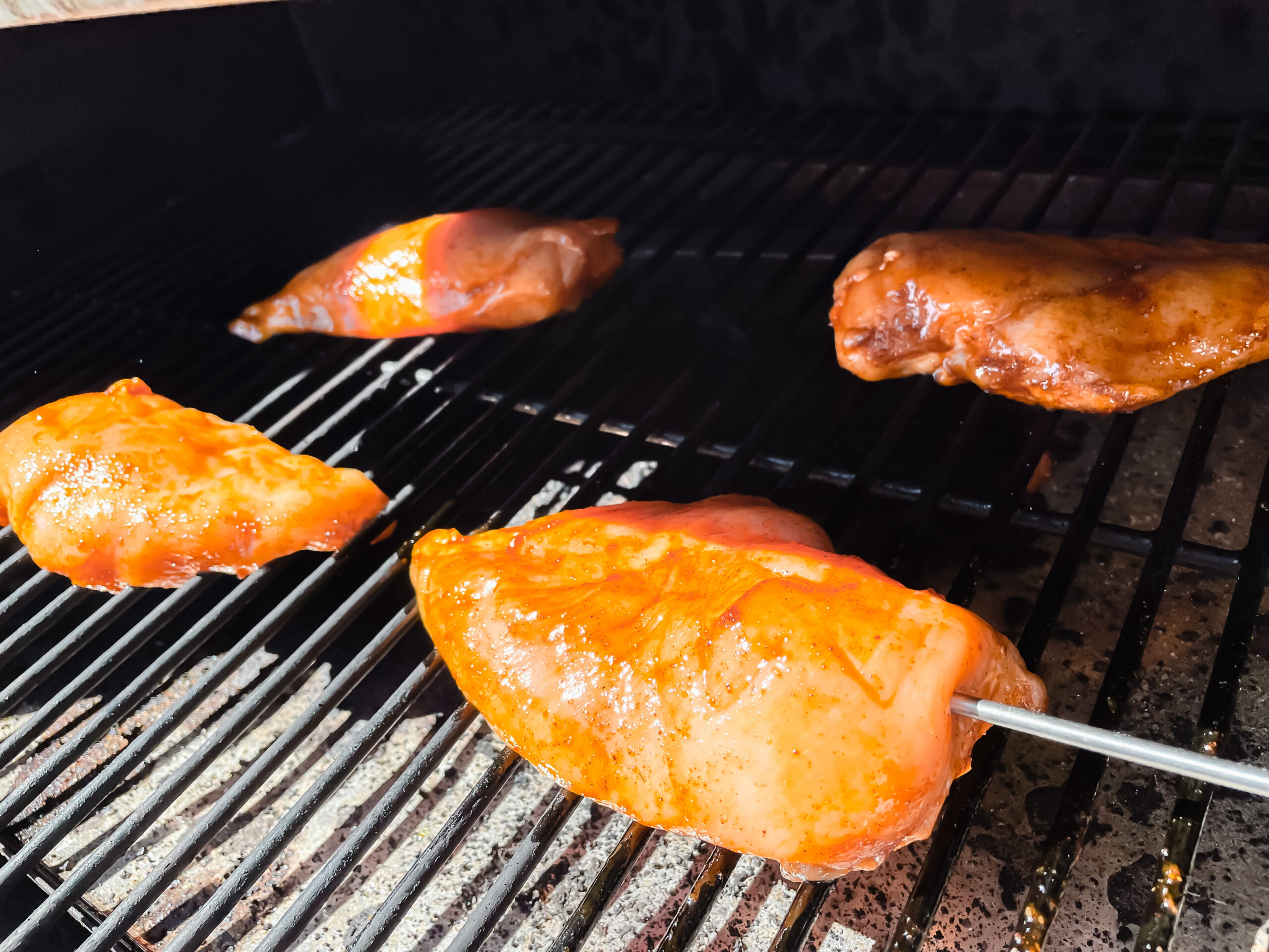 chicken breasts on a pellet grill with a probe in one of the breasts
