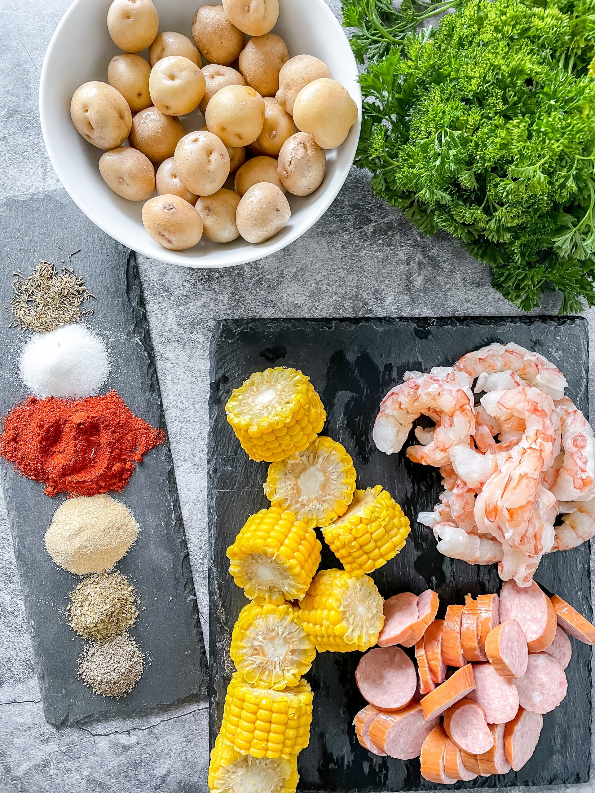 Ingredients for cajun boil in foil. parsley, potatoes, seasonings, shrimp. sausage and corn