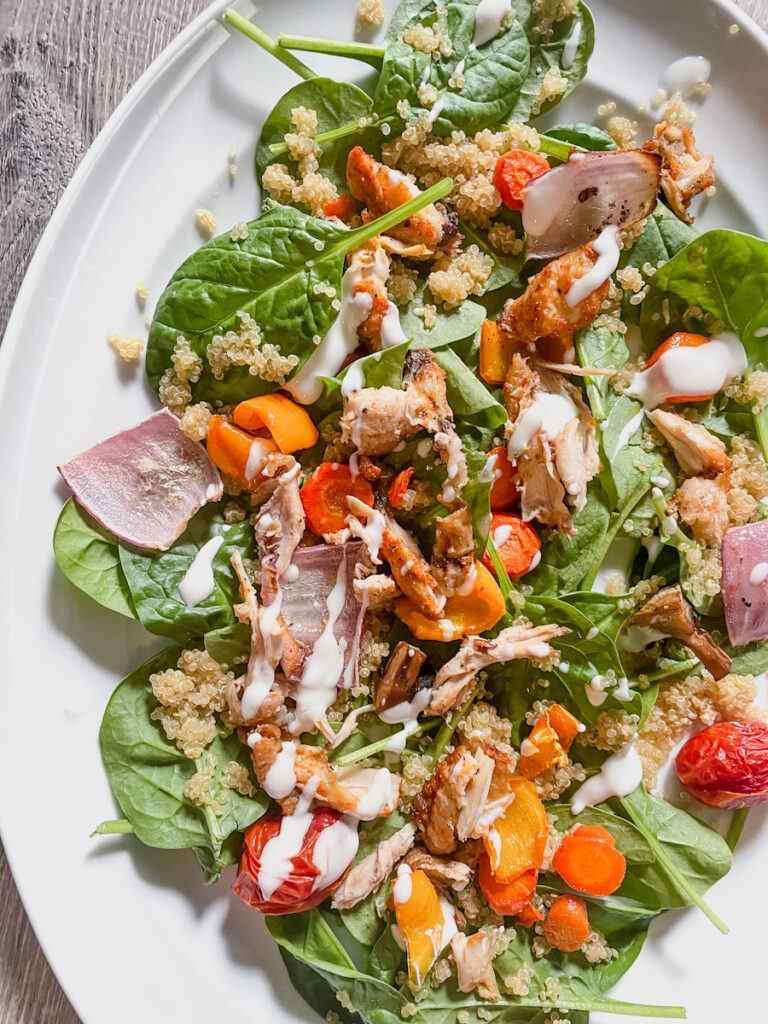 Roasted chicken and quinoa spinach salad in a bowl with roasted vegetables