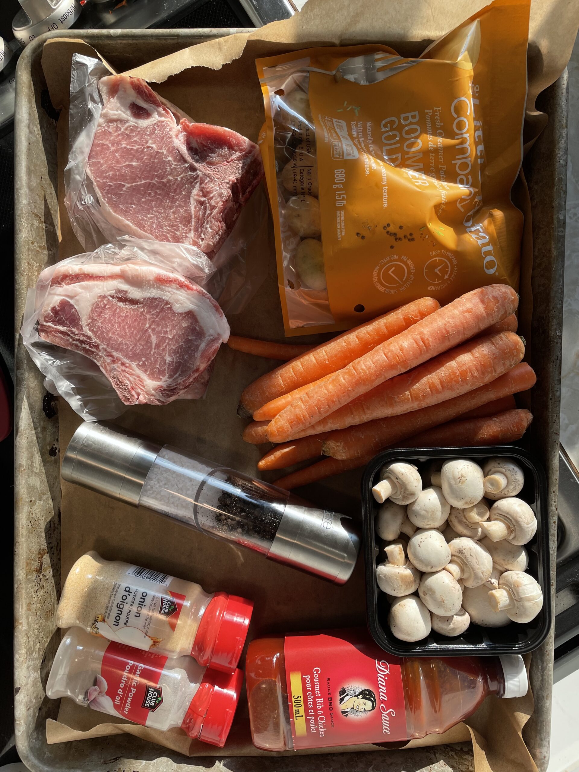 Ingredients On a sheetpan: potatoes, carrots, mushrooms, pepper and salt, seasonings, pork chops and pork chops 